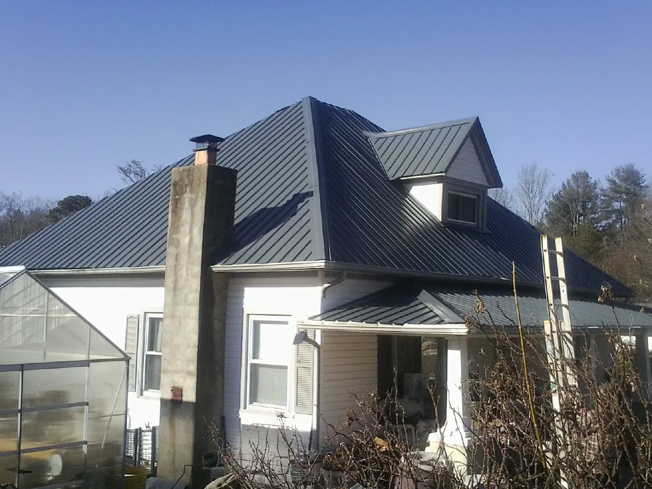 Dark blue standing seam metal roof on a white farmhouse with dormer — Slate & Tile Roof Repair by Roofing Brothers in Falcon