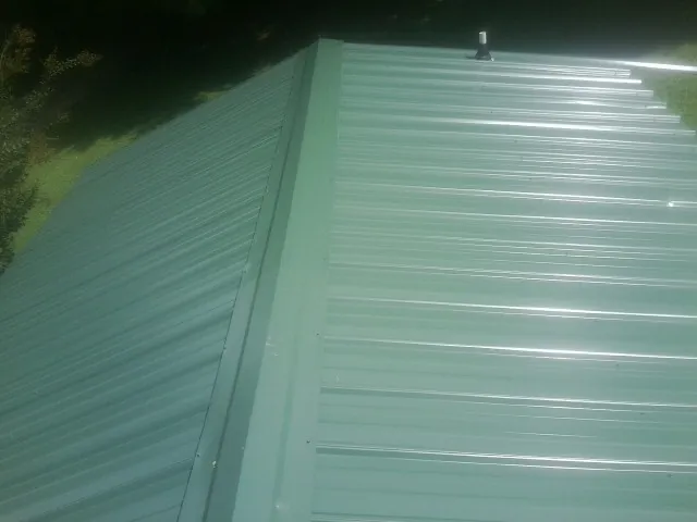 New green metal panels meeting at the ridge of a roof — Flat Roof Repair work by our crew in Falcon