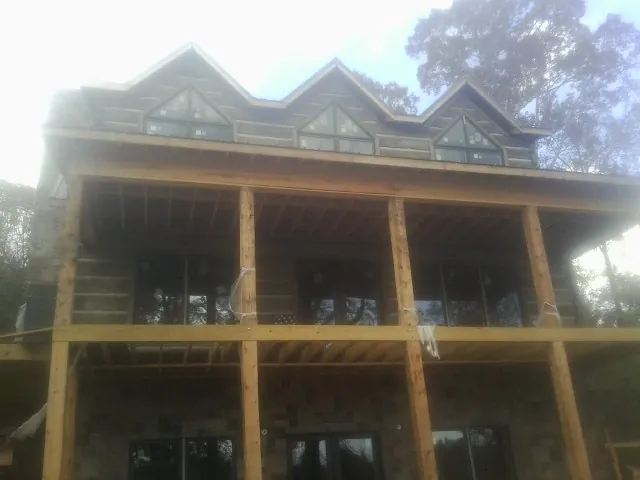 Dormers and porch framing on a large log home under construction — Roof Coating work by our crew in Falcon