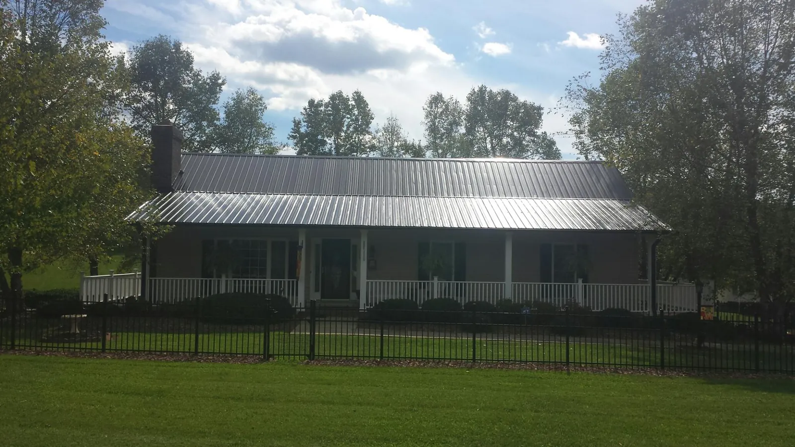 Gray metal roof on a brick ranch with a full width front porch — Gutter Guard Installation work by our crew in Falcon