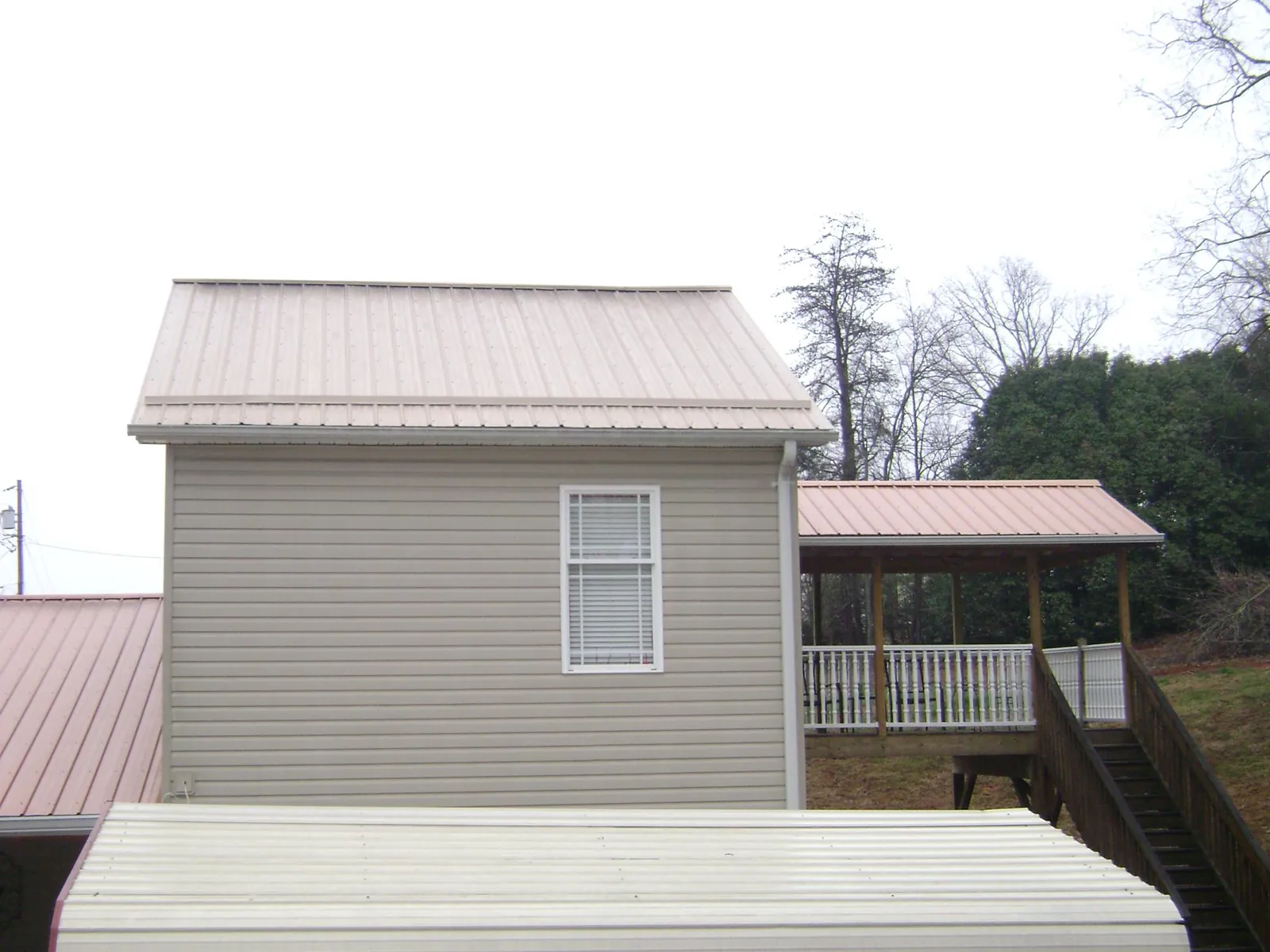 Tan metal roofs on a two story addition and attached porch, from a Roof Replacement job in Falcon