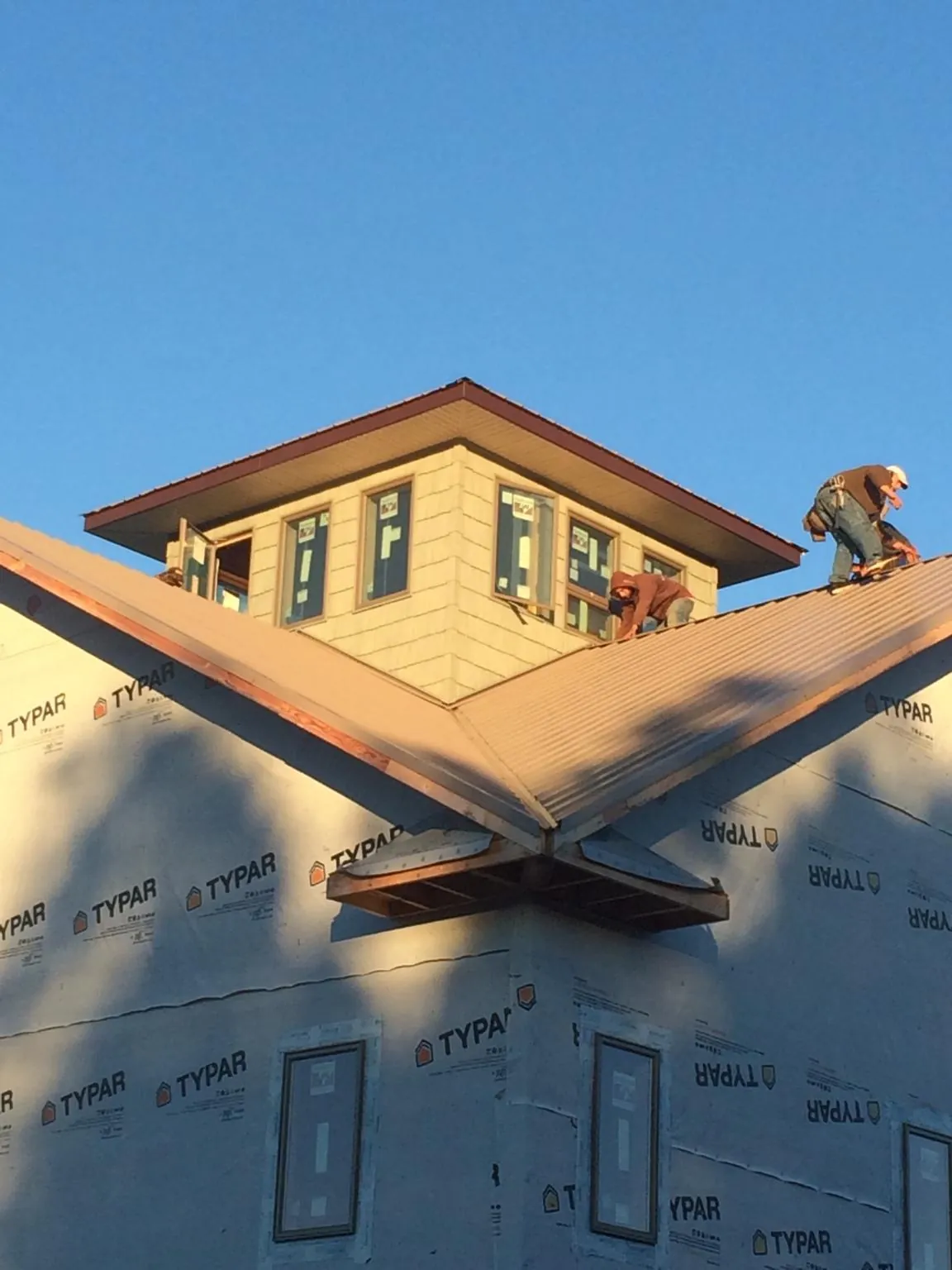 Roofers working around a rooftop cupola on a new metal roof at sunset — Roof Waterproofing in Falcon by Roofing Brothers